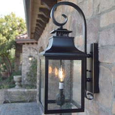 an outdoor wall light on the side of a stone building with two lights attached to it