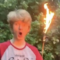 a young boy with blonde hair holding a fire stick