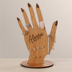 a wooden hand with rings on it that says arossa and is holding two fingers