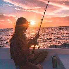 a woman sitting on the back of a boat while holding a fishing pole