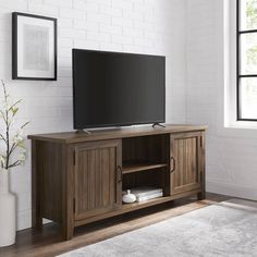 a flat screen tv sitting on top of a wooden entertainment center next to a window