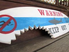 a wooden sign that says warning keep out of the water with shark and sharks on it