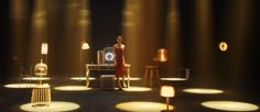 a woman standing in front of several lamps and stools on a dark stage with light streaming through them