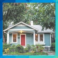 a small blue house with red door and windows in the front yard is surrounded by greenery