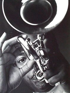 a black and white photo of a man holding a trumpet up to his face with both hands