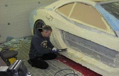 a man sitting on the ground working on a car