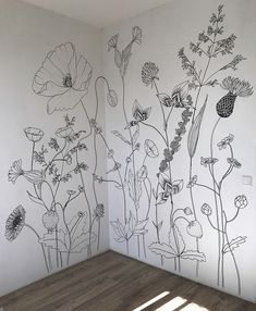 an empty room with flowers painted on the wall and wood flooring in front of it