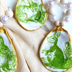 three green and white ceramic pendants with beads on a plate next to each other