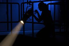 a person sitting in a jail cell with a light shining on her and behind them