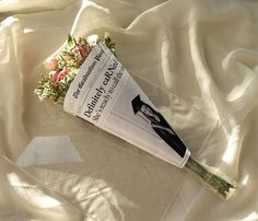 a book laying on top of a bed covered in white sheets with flowers next to it