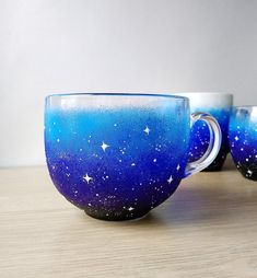 three coffee cups sitting on top of a wooden table covered in blue and white paint