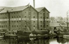 an old black and white photo of boats in front of a brick building with banners on it