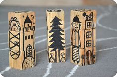 three wooden blocks with designs on them sitting in front of a line of track markings