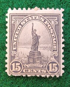 an old postage stamp with the statue of liberty on it's back side in green grass