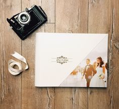 an open book with a wedding photo on it next to a couple's camera