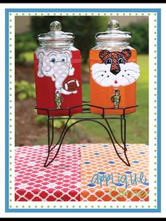 two metal canisters sitting on top of a red and orange tablecloth covered table