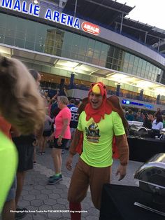 a man dressed as a lion in front of a mall arena with people walking around