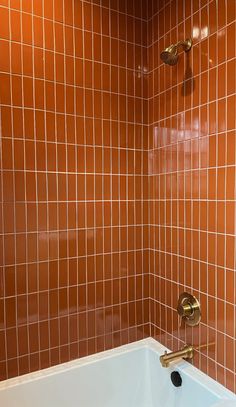 a bath tub sitting under a faucet next to a shower head in a bathroom