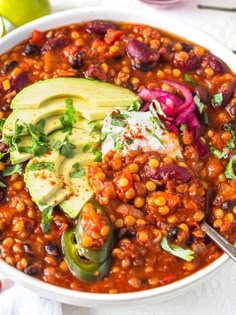 a white bowl filled with beans, avocado and other vegetables on top of a table