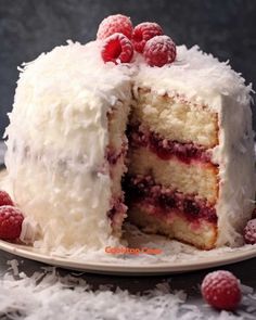 a cake with white frosting and raspberries is cut in half on a plate