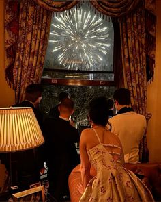 two men and a woman looking out the window at fireworks