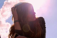 a woman is holding her cell phone to her ear and looking up into the sky