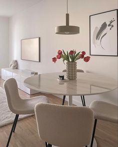 a dining room table with four chairs and a vase filled with flowers on top of it