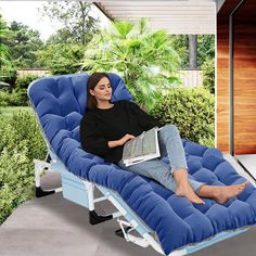 a woman sitting on a blue chaise lounge chair with a laptop in her lap