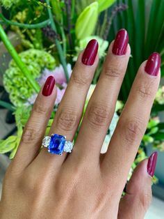 a woman's hand with red nails and a blue ring