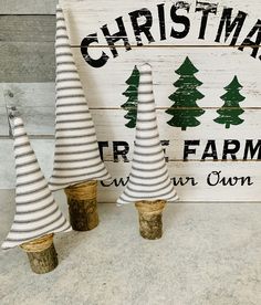 three small christmas trees sitting next to each other on top of a wooden sign that says christmas tree farm