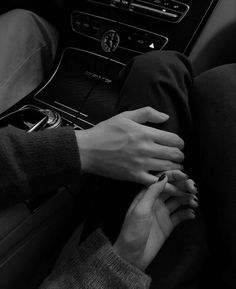 two hands on the steering wheel of a car, one holding the other's hand