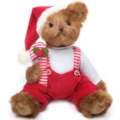 a brown teddy bear wearing a santa hat and overalls sitting on a white surface