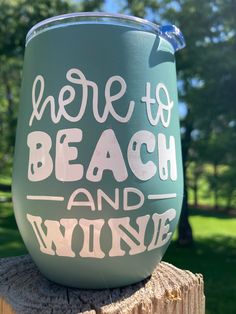 there is a wine glass that says here to beach and wine on top of a tree stump