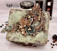 an old box with some flowers and butterflies on it sitting on a table next to other items