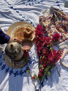 a table topped with plates and cups filled with food on top of a white table cloth