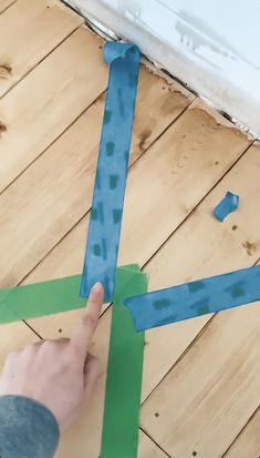 someone is cutting out some tape on the floor to make a pattern for something else