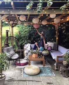 a woman sitting on top of a couch under a pergoline covered patio area