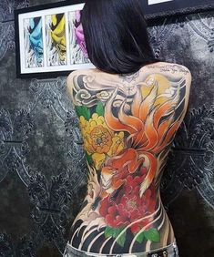 the back of a woman's body with tattoos on it