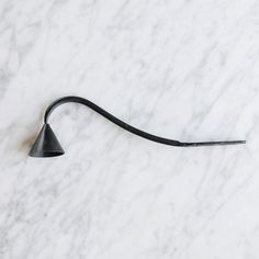 a pair of black scissors sitting on top of a white marble countertop next to a metal hook