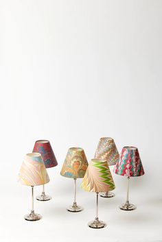 five lamps with different designs on them sitting next to each other in front of a white wall