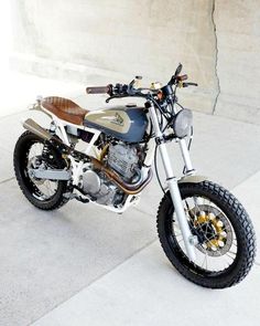 a motorcycle is parked on the sidewalk near a wall and cement floored area with concrete walls in the background