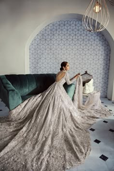 a woman sitting on top of a green couch in a white dress with long sleeves