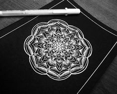 a pen is sitting on top of a black notebook with a white flower in the middle