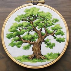 a cross stitch tree with green leaves on it