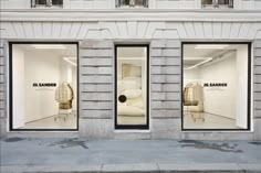 an empty store front with three large windows on each side and two chairs in the window