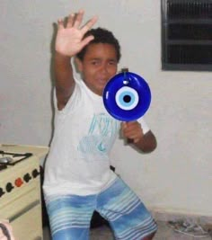 a young man holding a blue frisbee in his right hand with an evil eye on it