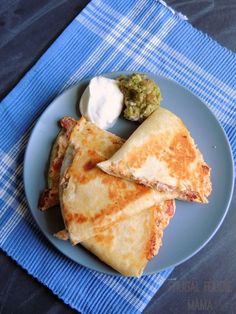 two quesadillas on a blue plate with sour cream