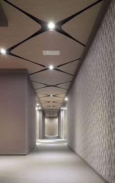 an empty hallway with lights on the ceiling and carpeted walls in front of it