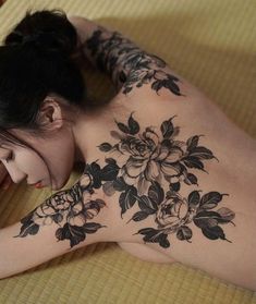 a woman laying on top of a bed next to a pillow covered in black and white flowers