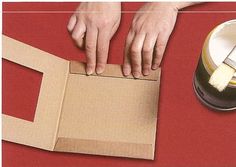 a person cutting out a piece of cardboard with a knife and tape on top of it